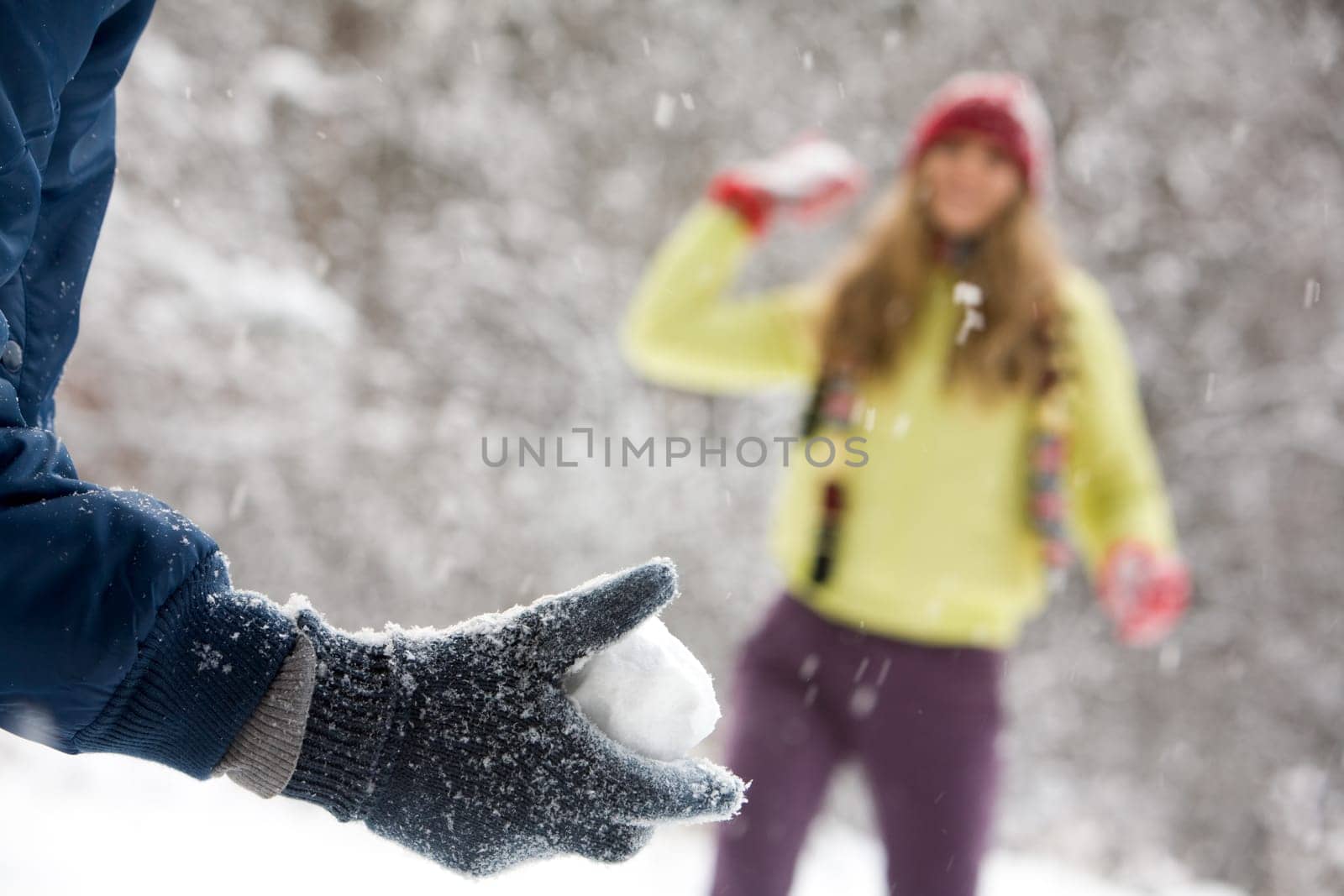 Portrait of woman throwing snow to man outdoor