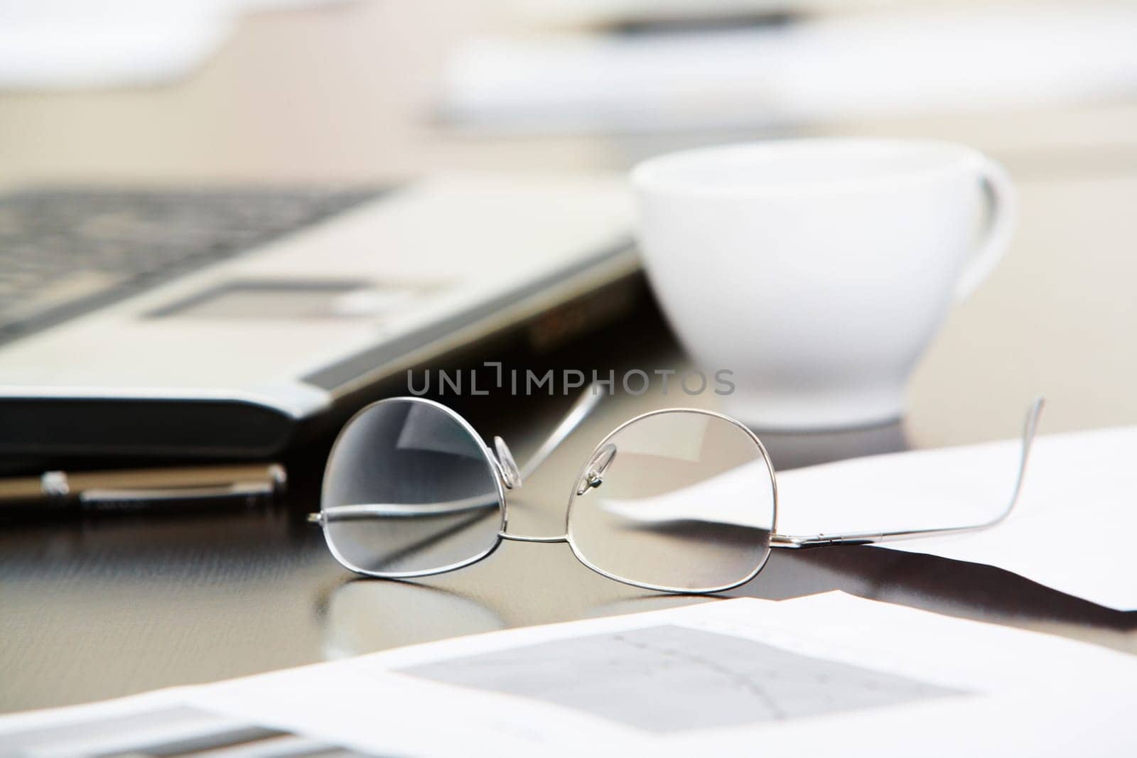 Close-up of papers, glasses and cup on workplace