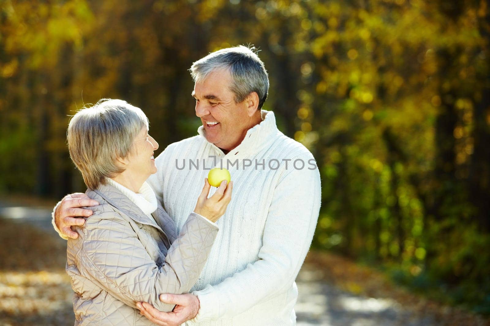 Photo of amorous aged man and woman holding apple and looking at each other