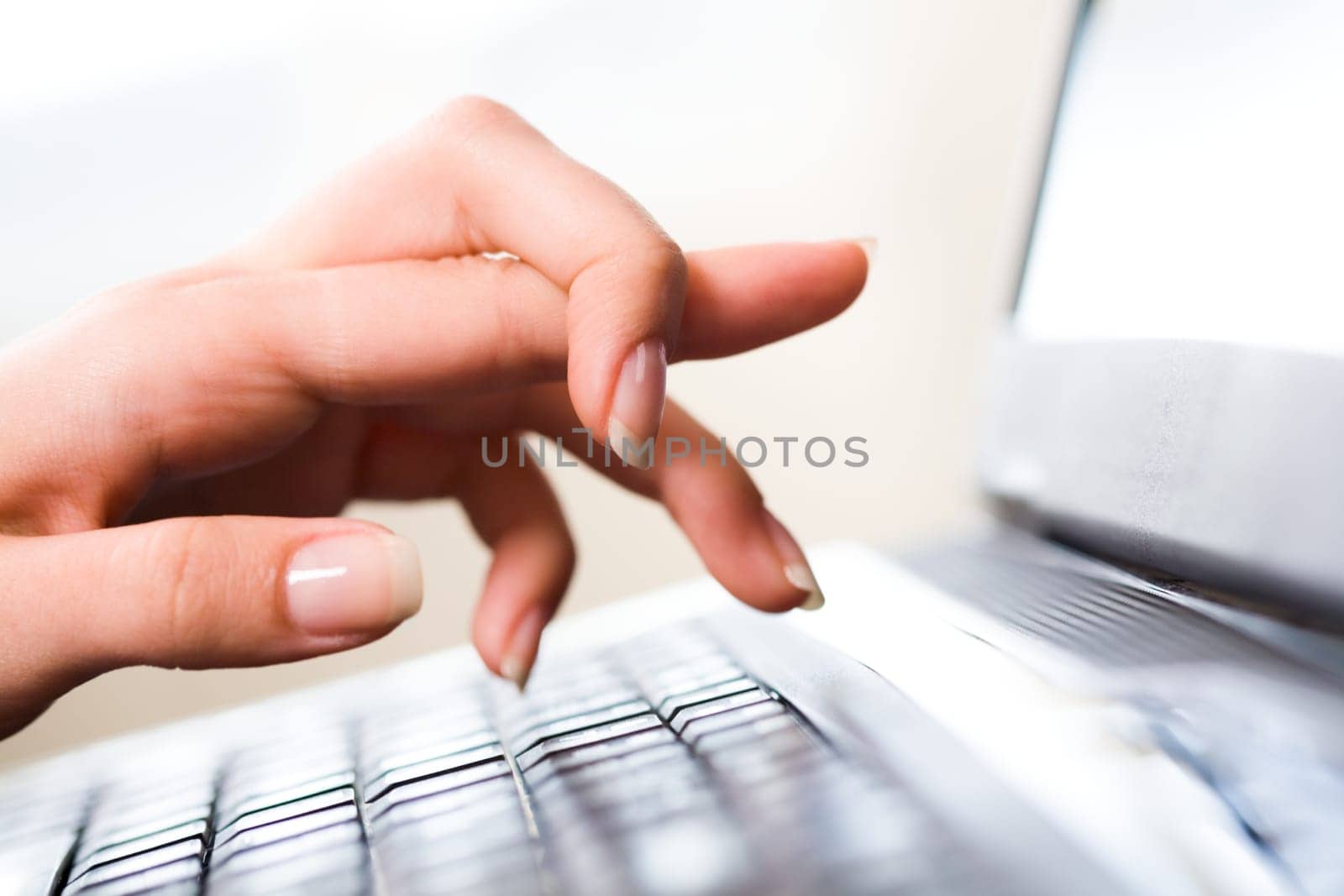 Close-up of female hand keeping forefinger bound while pointing at laptop display