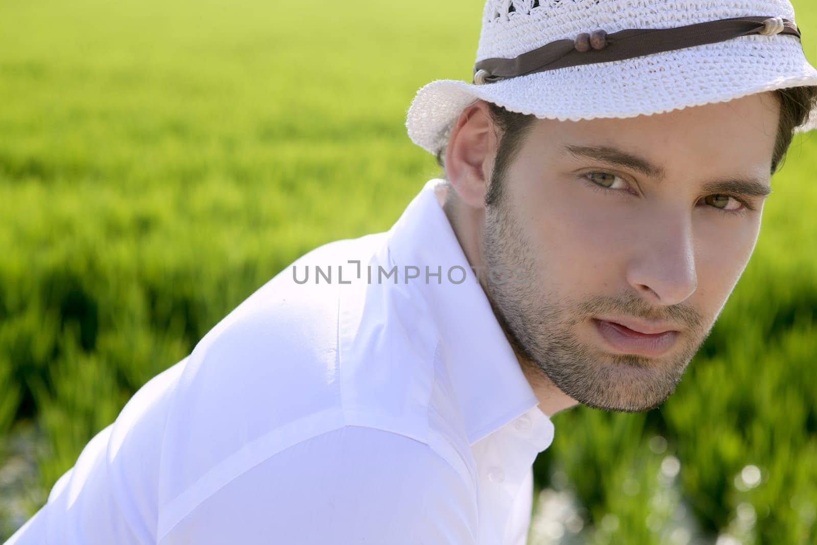 Mediterranean man portrait white hat in green meadow rice field