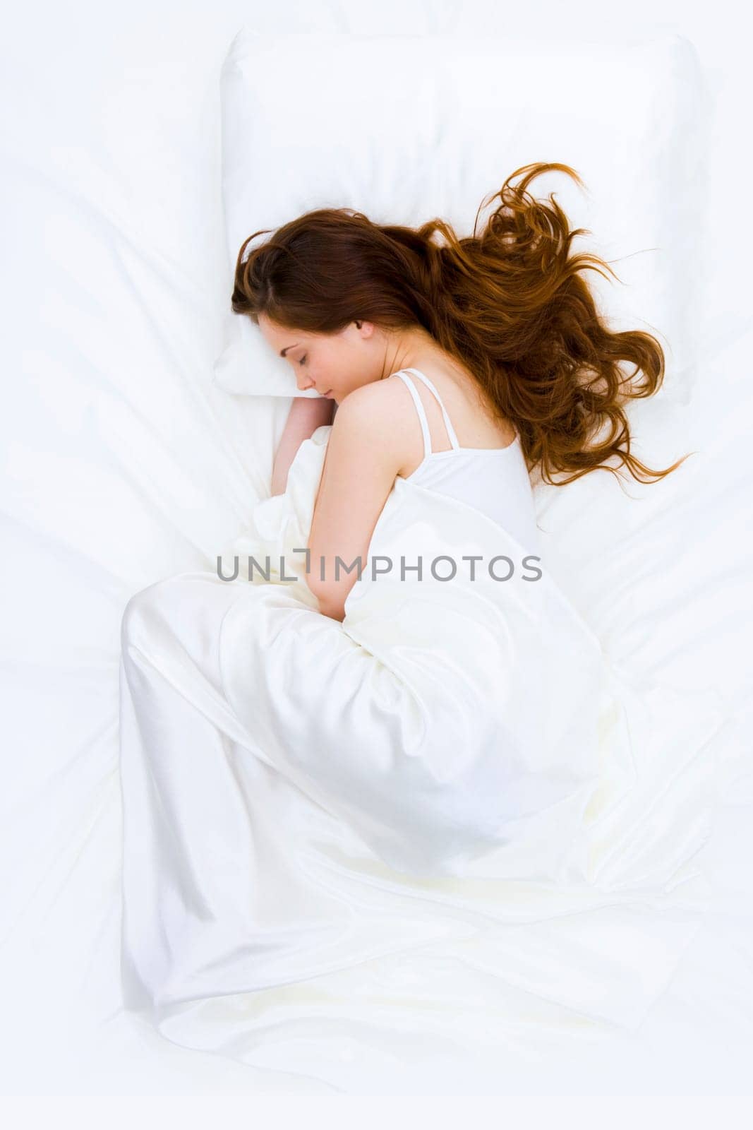 Serene woman covered with silk cloth lying in bed and having a nap