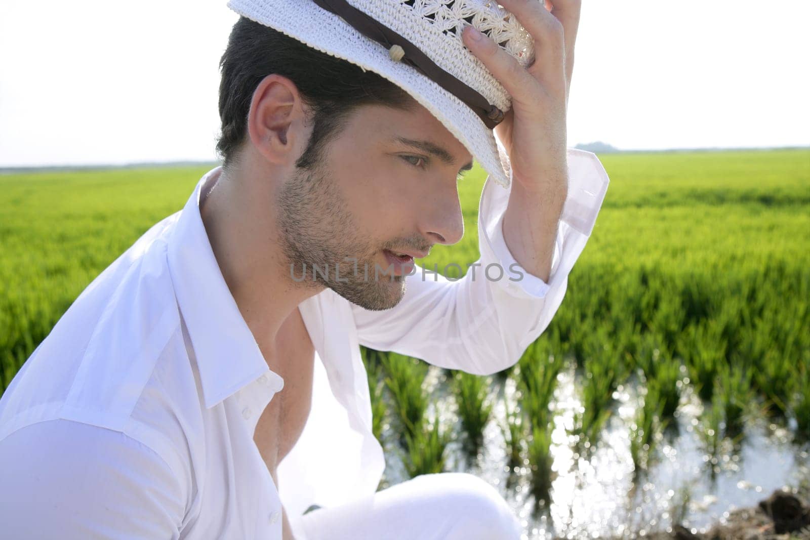 Mediterranean man portrait white hat in green meadow rice field