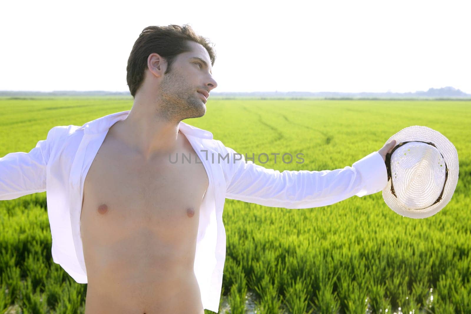 Summer man open shirt outdoor meadow with white hat in hand