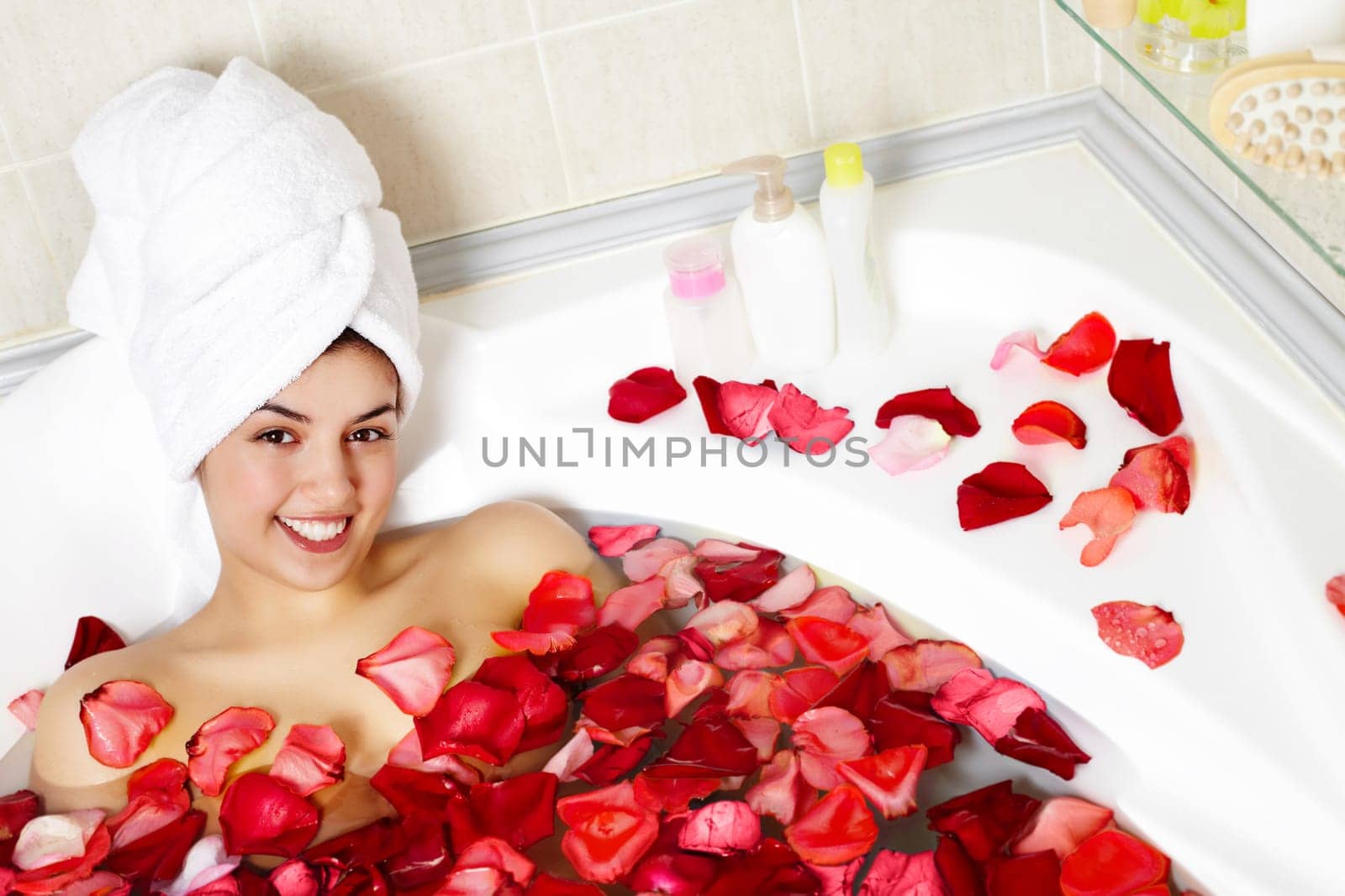 Portrait of happy female in water surrounded by rose petals