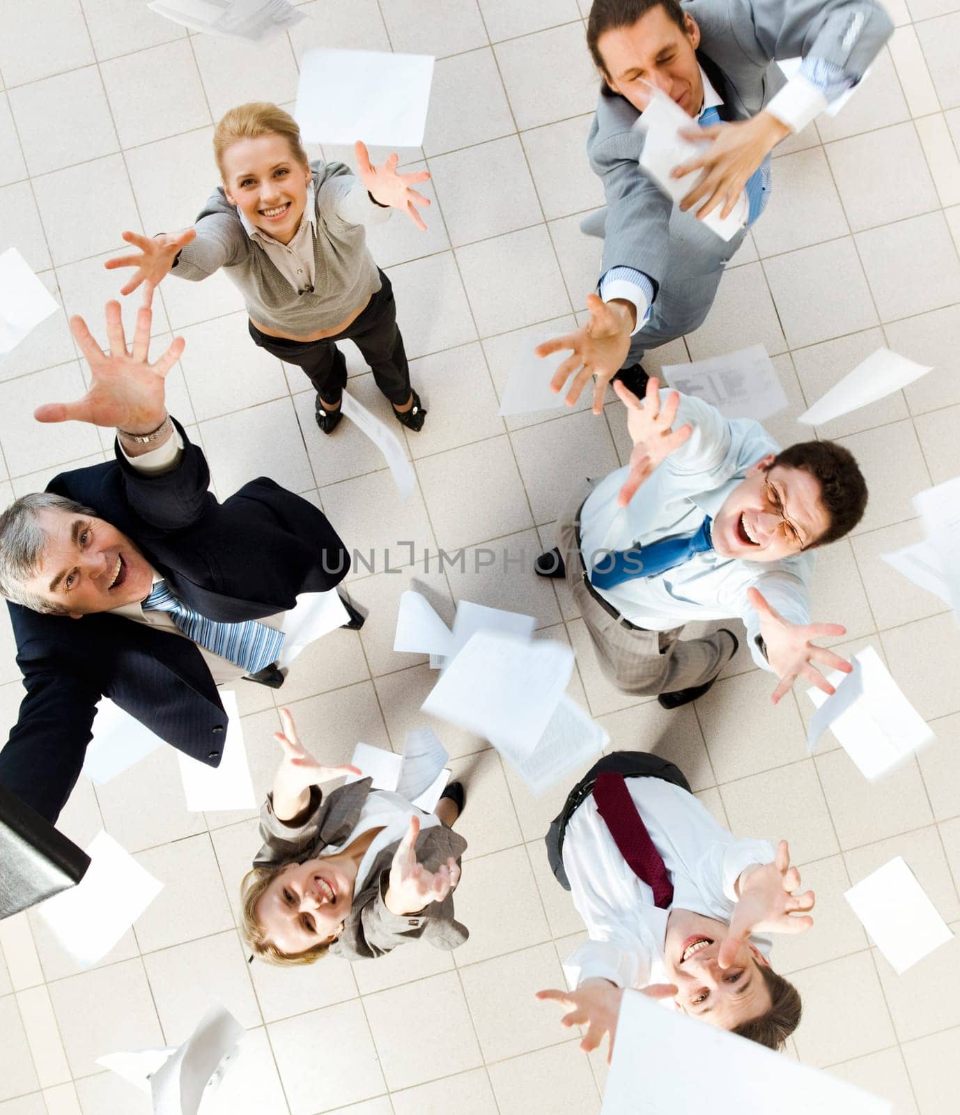 Above view of several successful partners throwing papers in joy