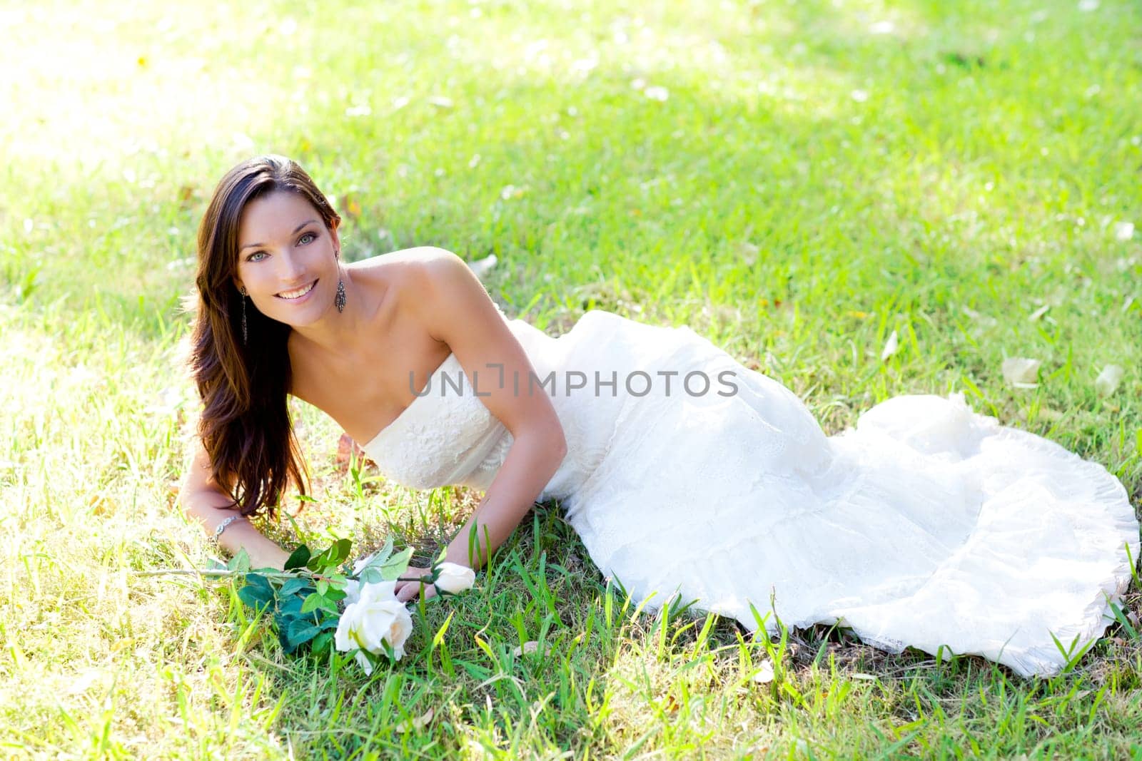 bride woman lying in park grass with white rose