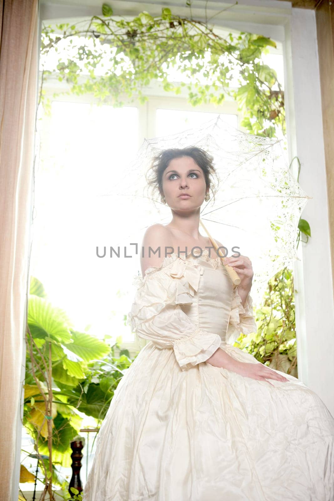 Victorian beautiful woman, white dress at home window with plants