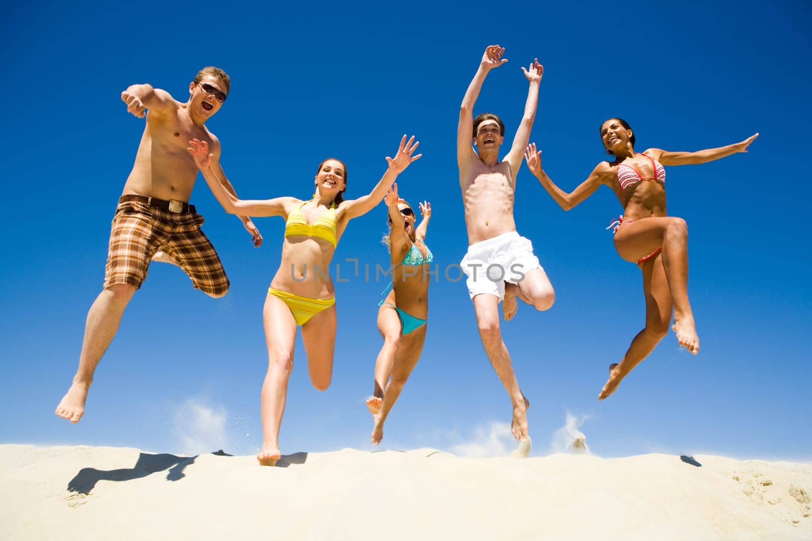 Image of five energetic people jumping at the beach