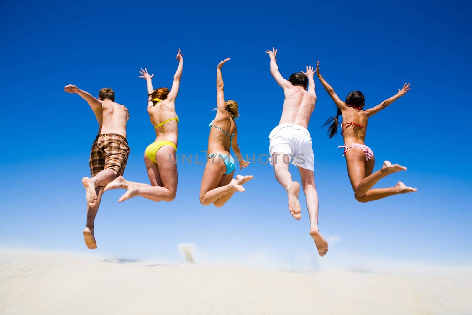Portrait of jumping young people a backs on the beach