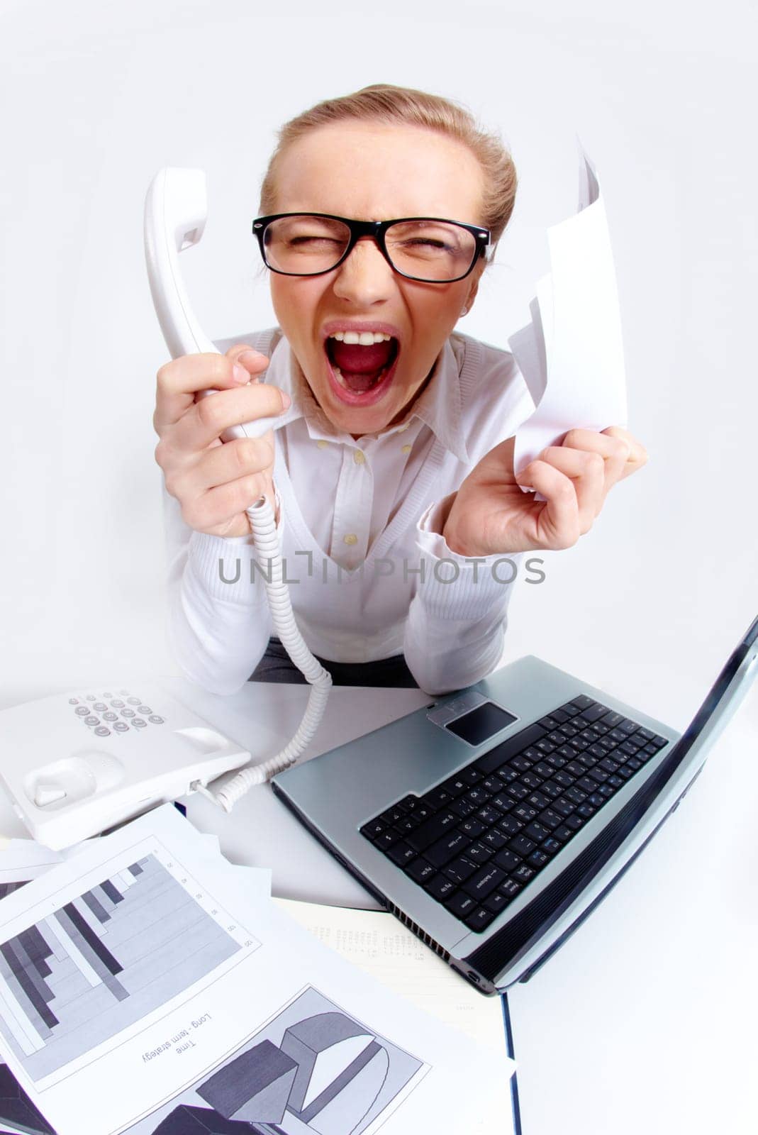 Photo of exhausted secretary shouting with phone receiver and paper in hands while sitting in office