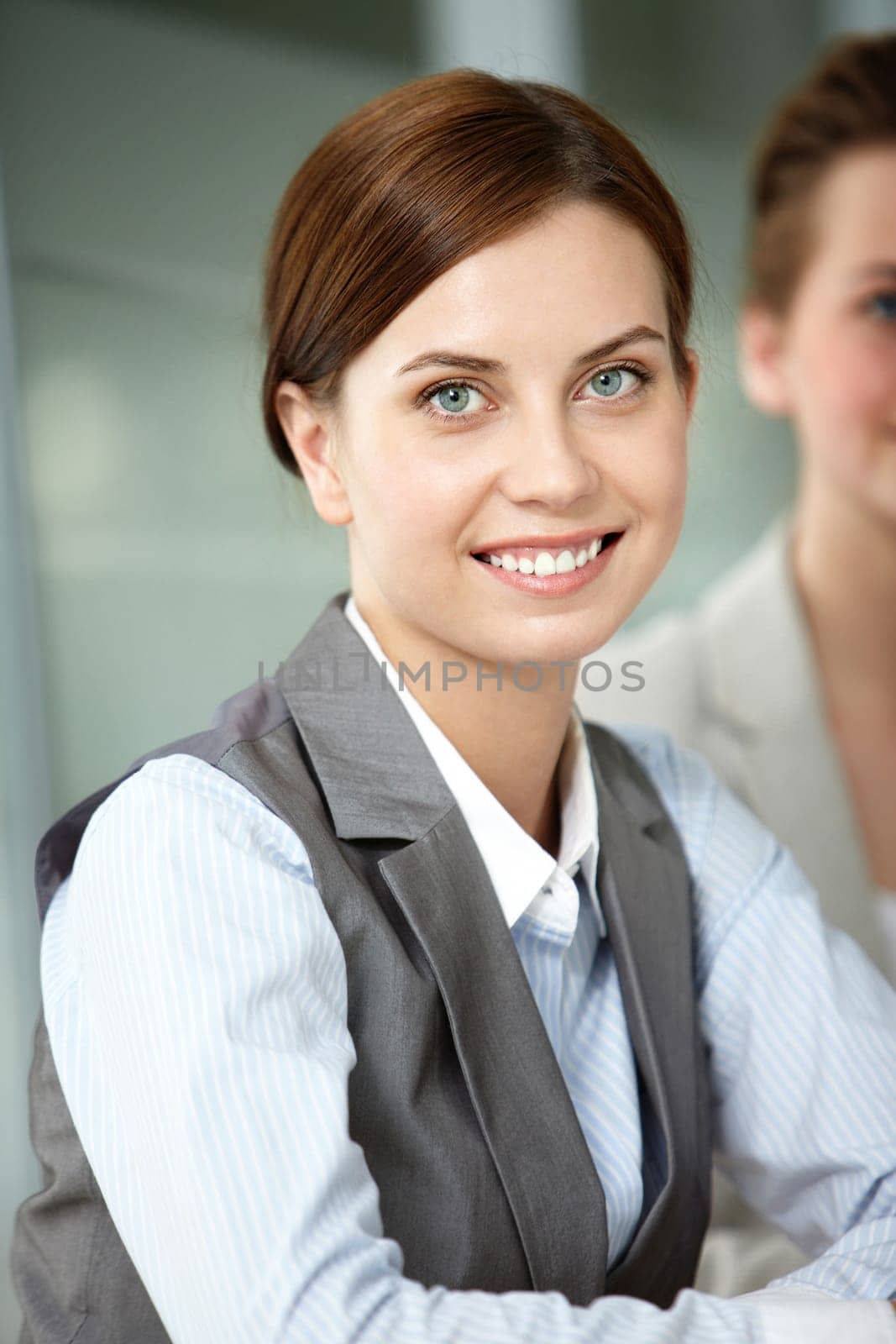 A beautiful businesswoman looking at camera with partner behind
