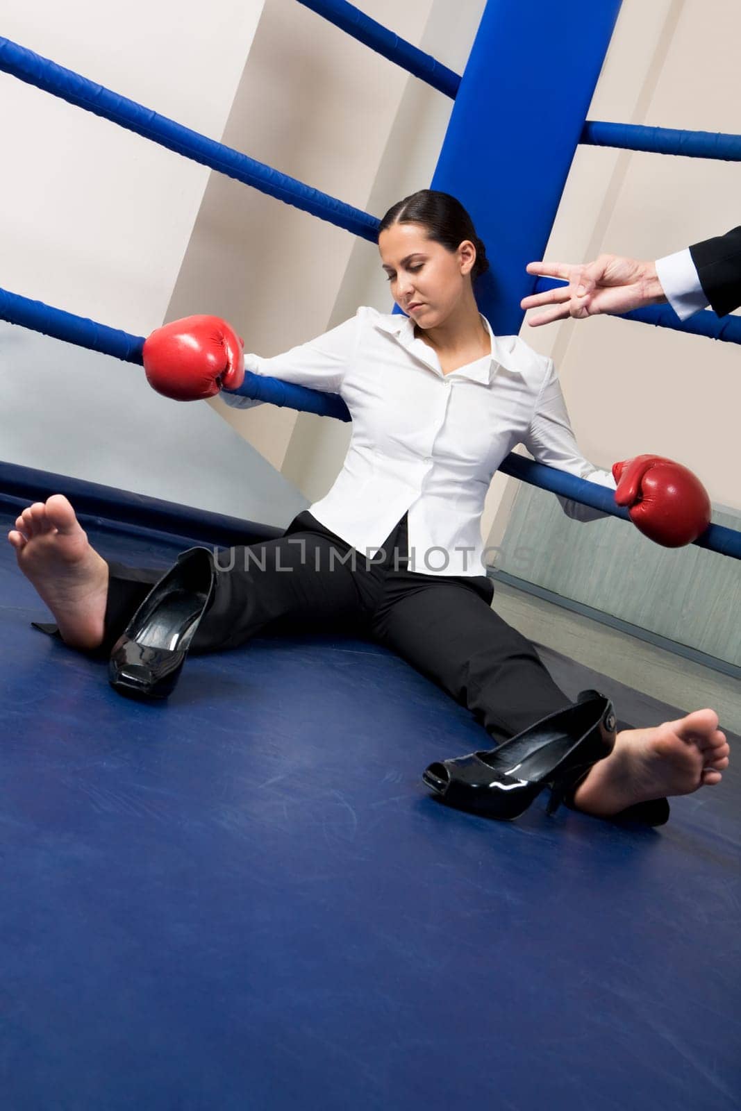 Portrait of tired businesswoman in boxing gloves sleeping on boxing ring