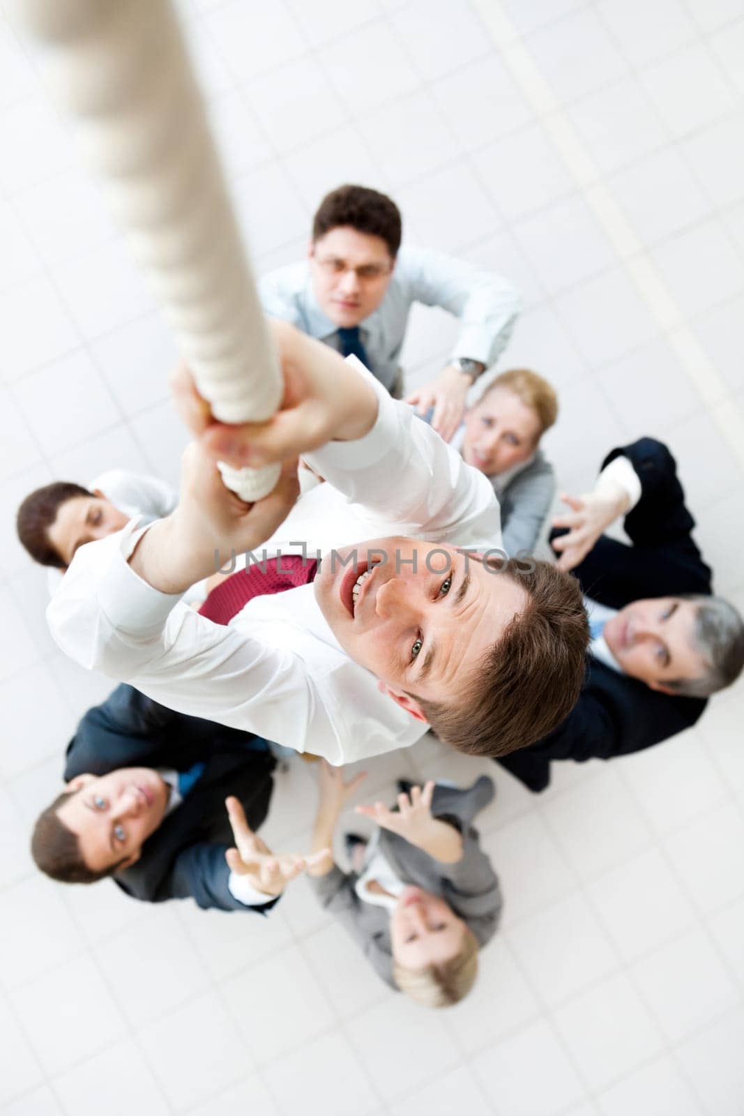 Above view of businessman ascending up the rope with his crew beneath