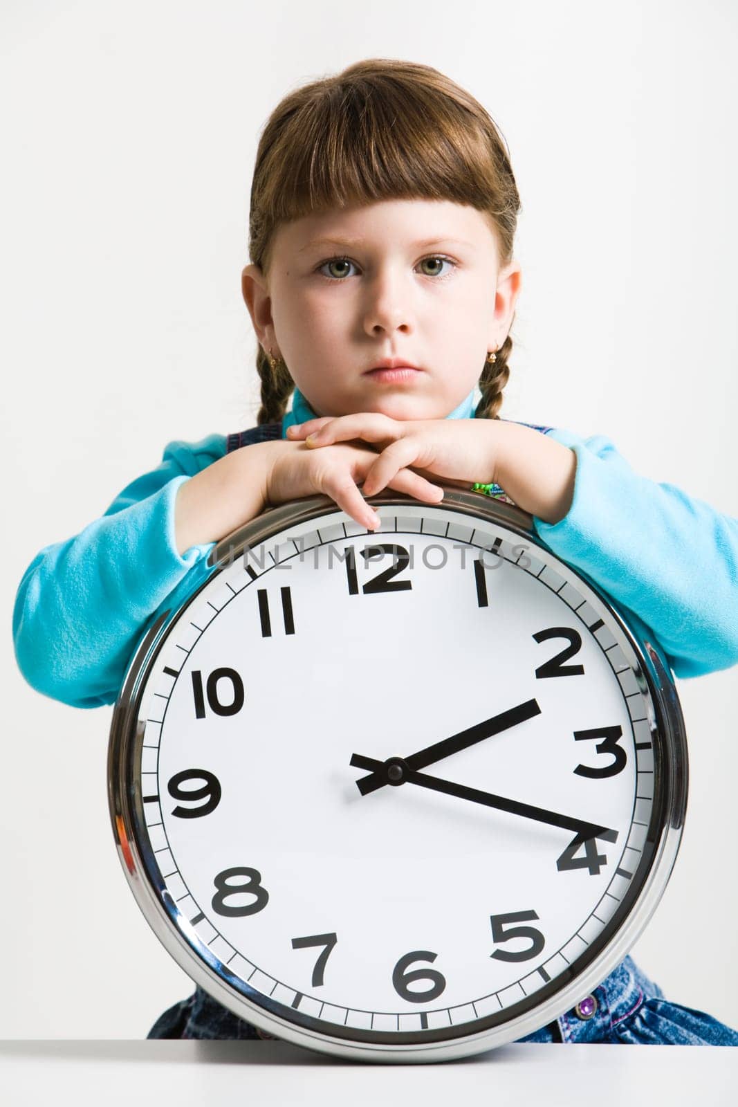 Cute little girl with big clock watching in a serious way