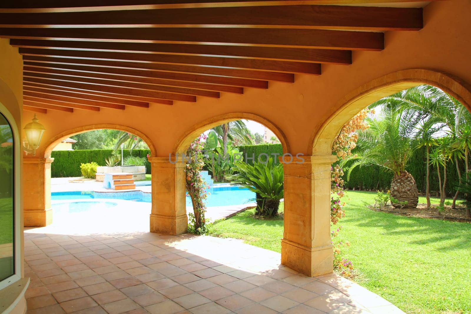 colonnade archs house in yellow on blue swimming pool garden