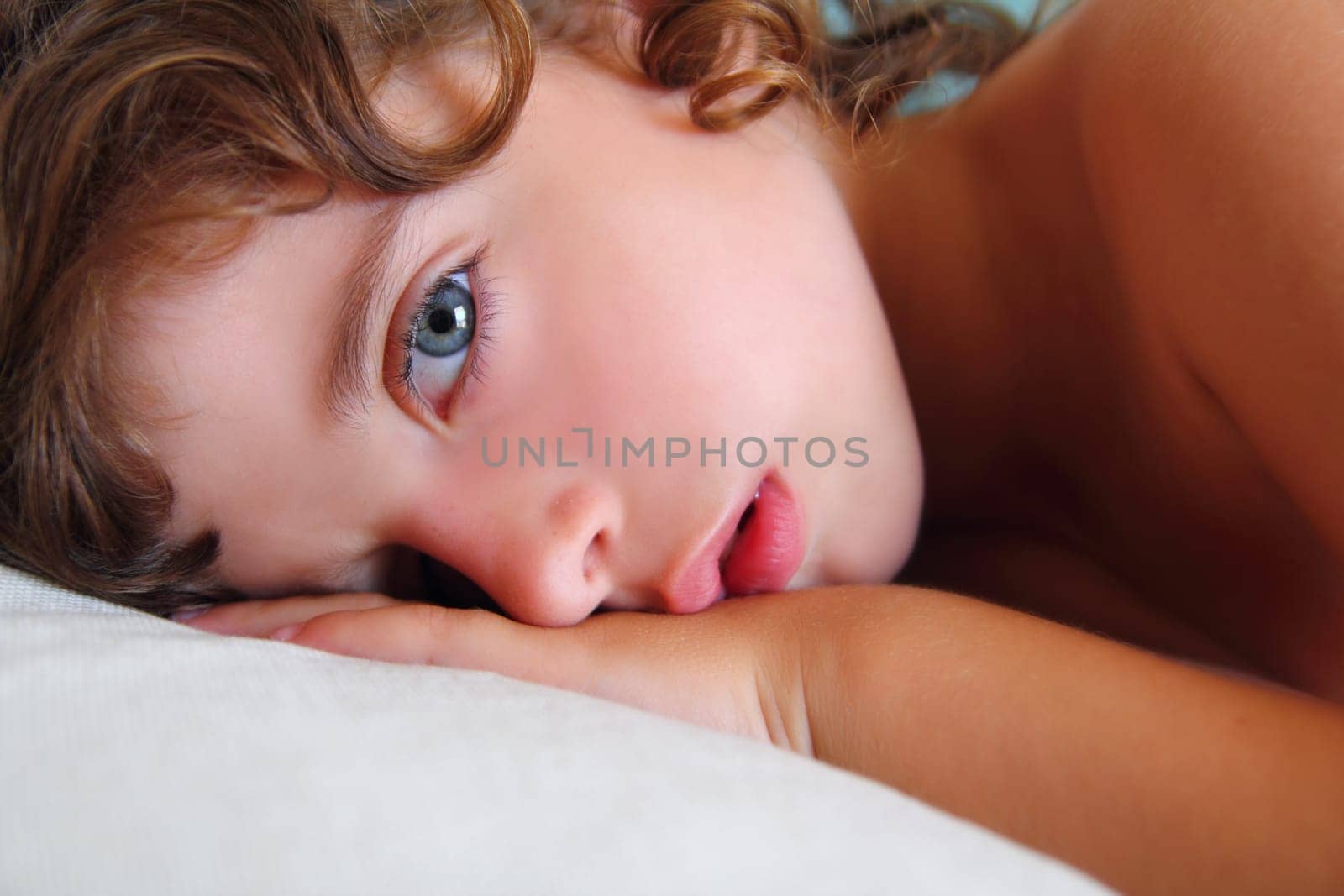 child girl relaxed on pillow looking camera with blue eyes