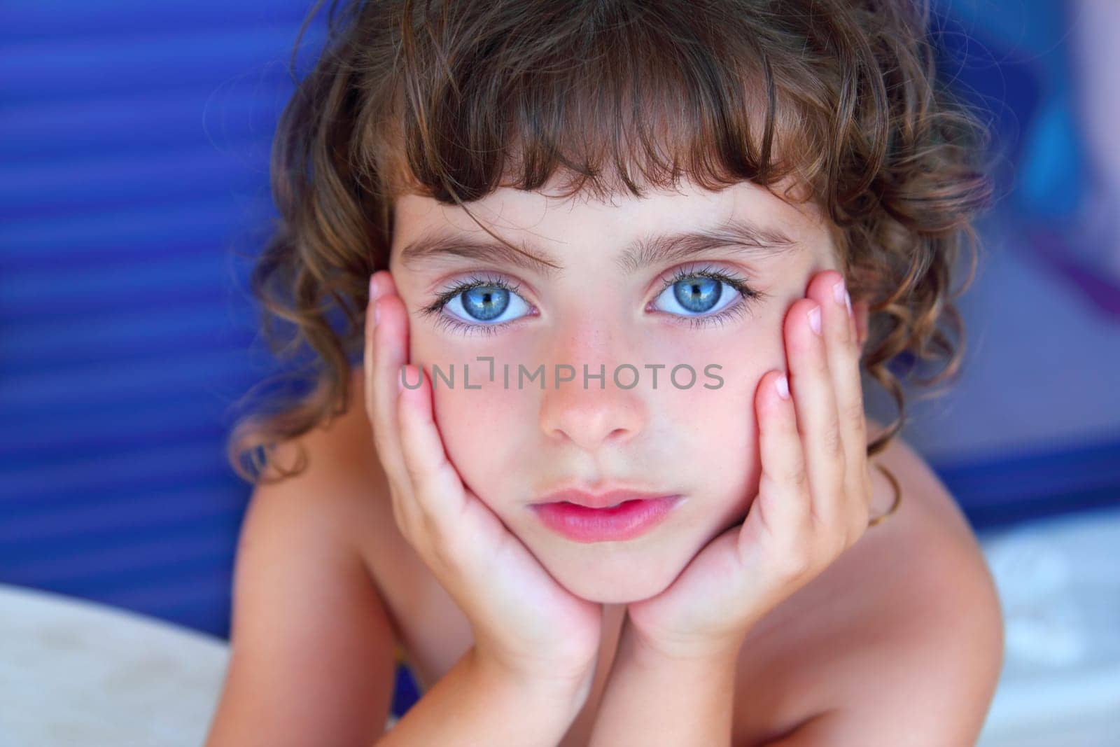 Beautiful blue eyes serene little girl portrait hands on face