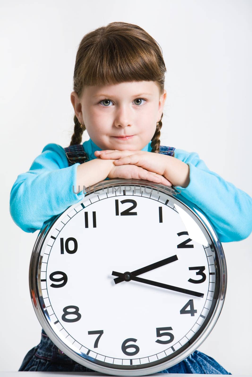 Portrait of serious girl with clock looking at camera