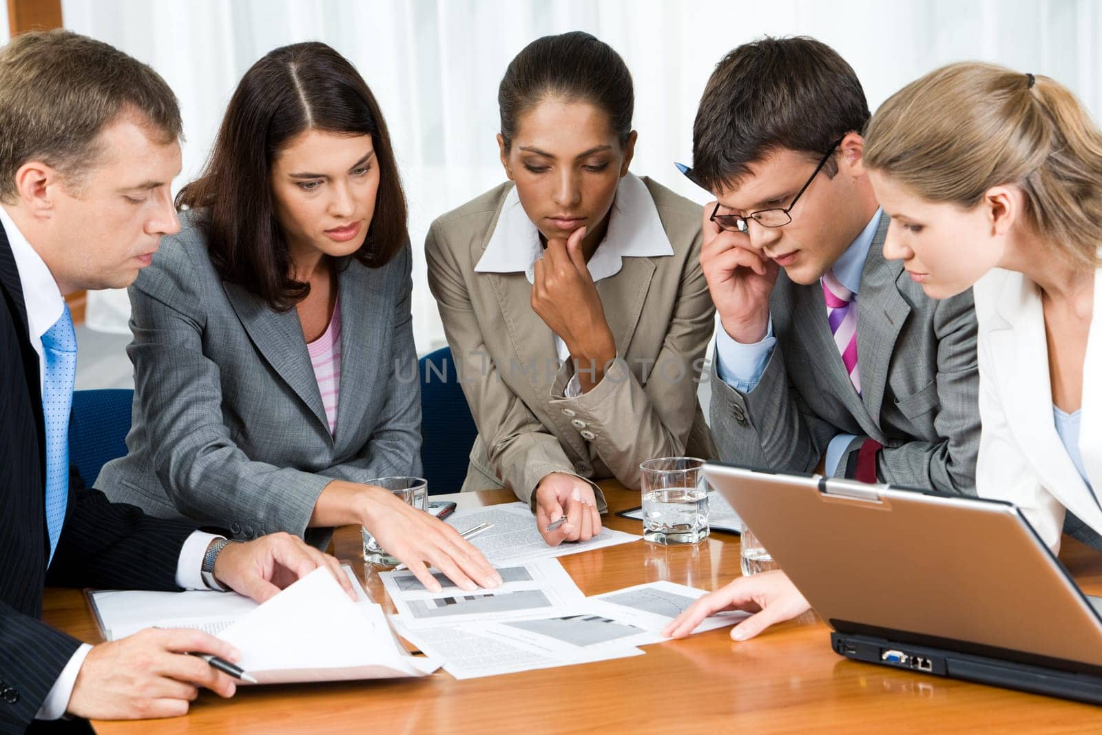 Portrait of confident people looking seriously at business papers during working meeting