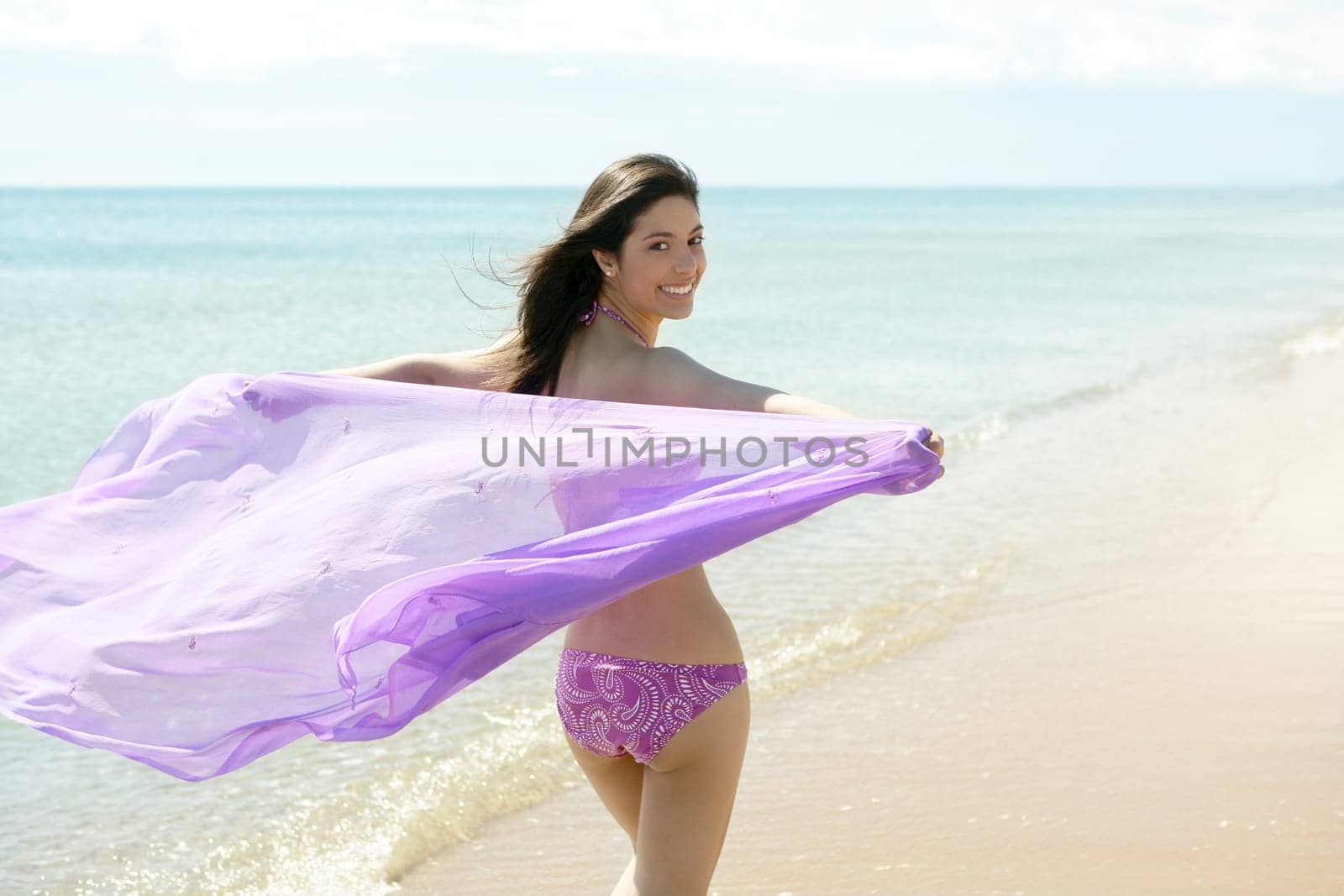 beautiful woman running on the beach, purple bikini