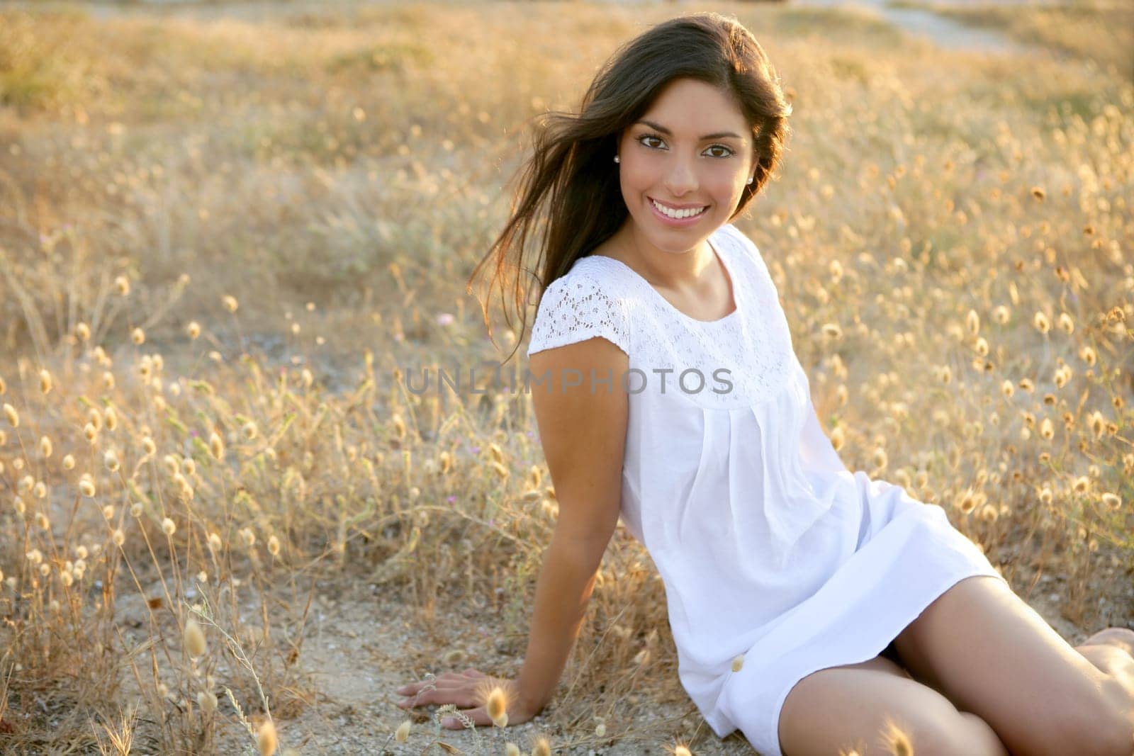 Beautiful indian brunette having a rest on a golden summer field