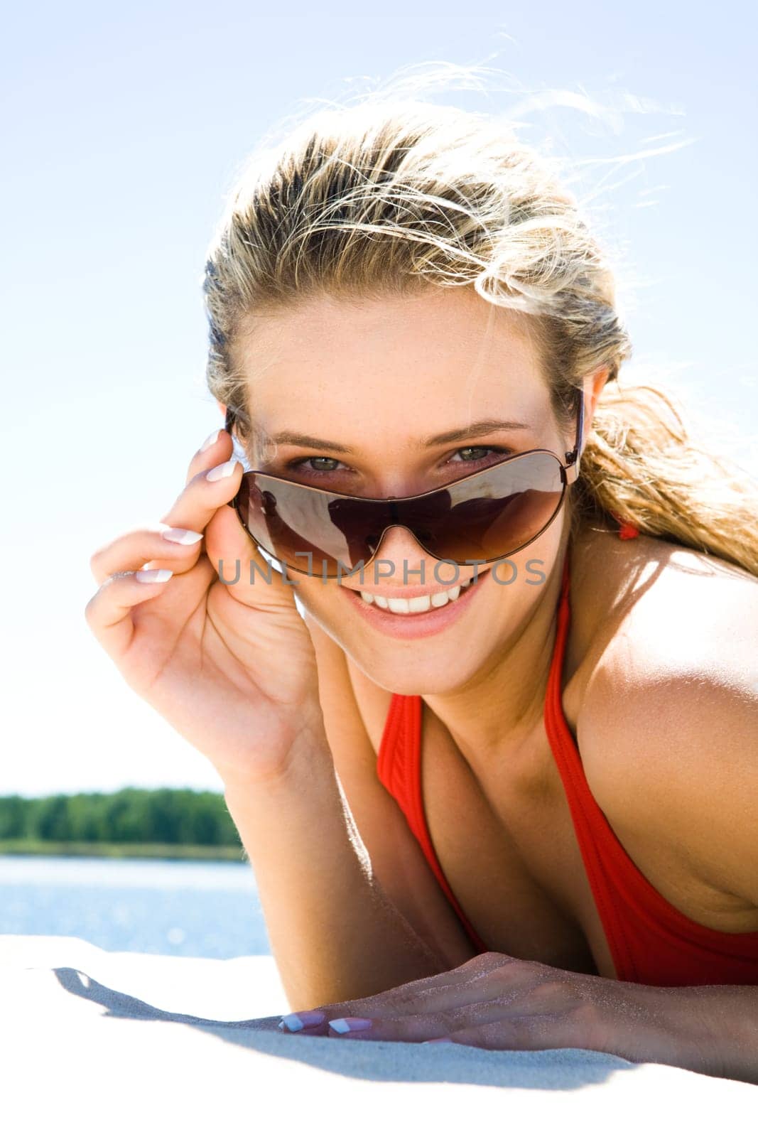 Portrait of blonde touching her sunglasses and looking at camera