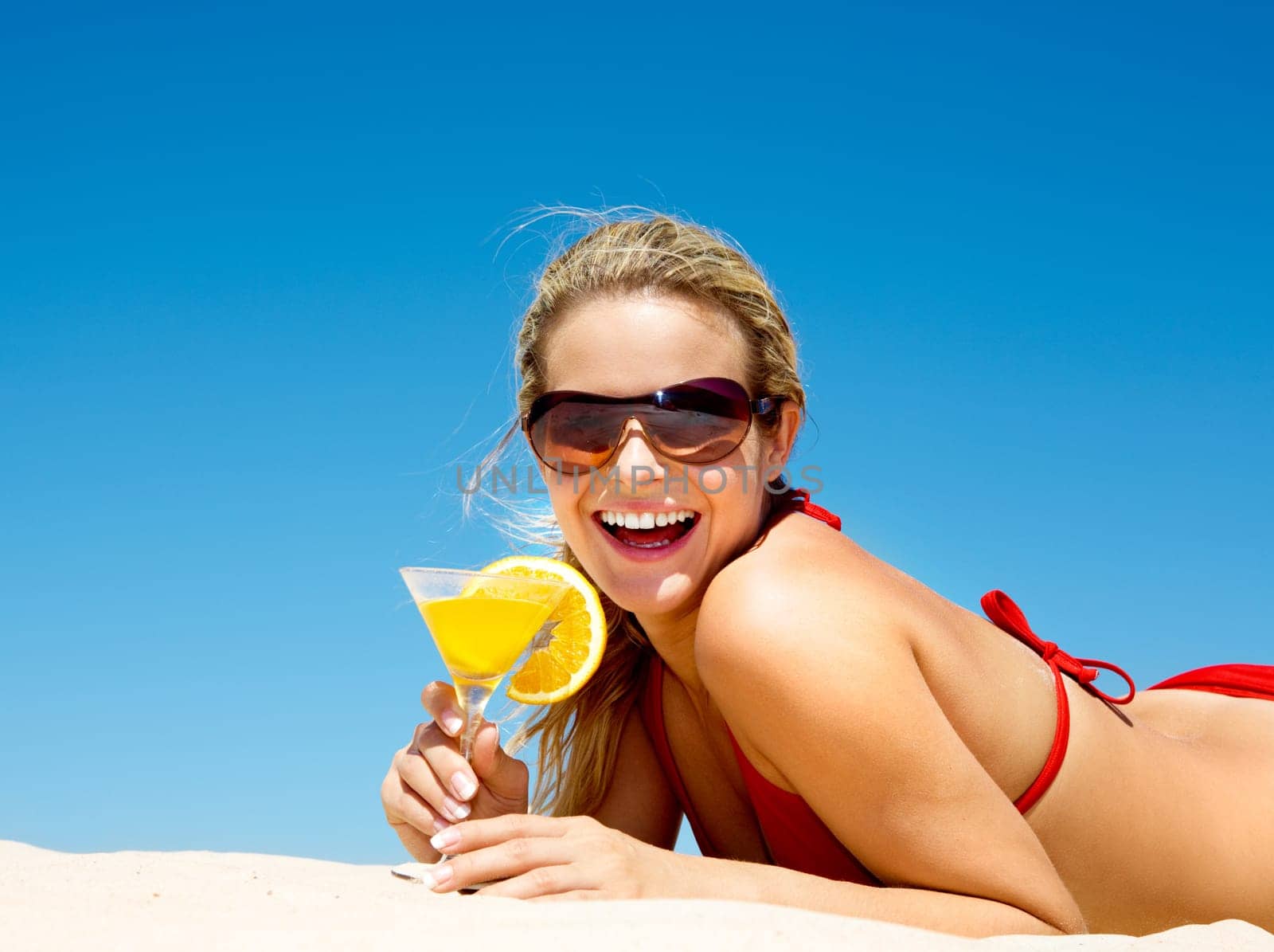 Portrait of happy woman wearing sunglasses holding cocktail at summer