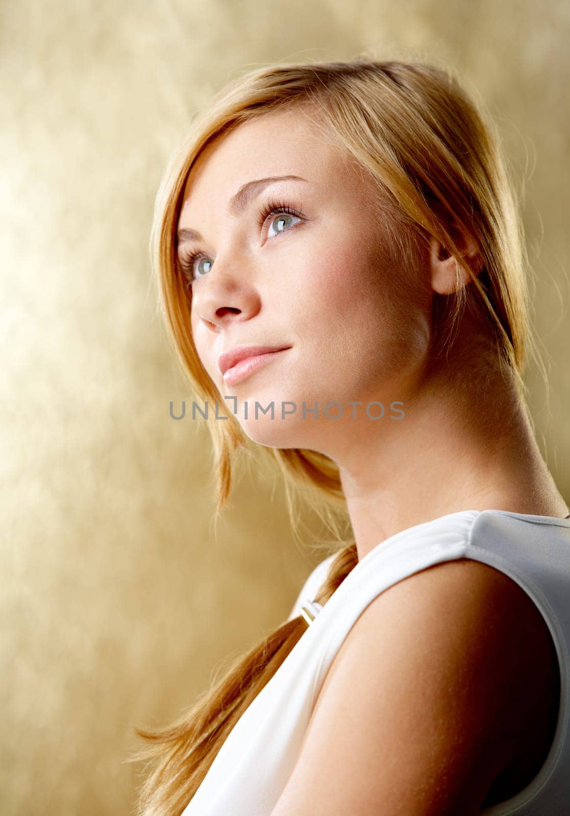 Portrait of pretty girl looking aside with smile over golden background