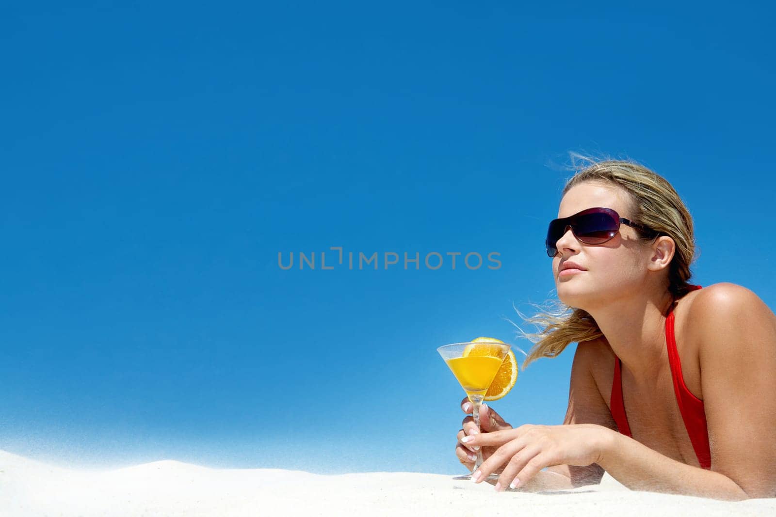 Portrait of charming woman with orange cocktail and sunglasses on the background of sky