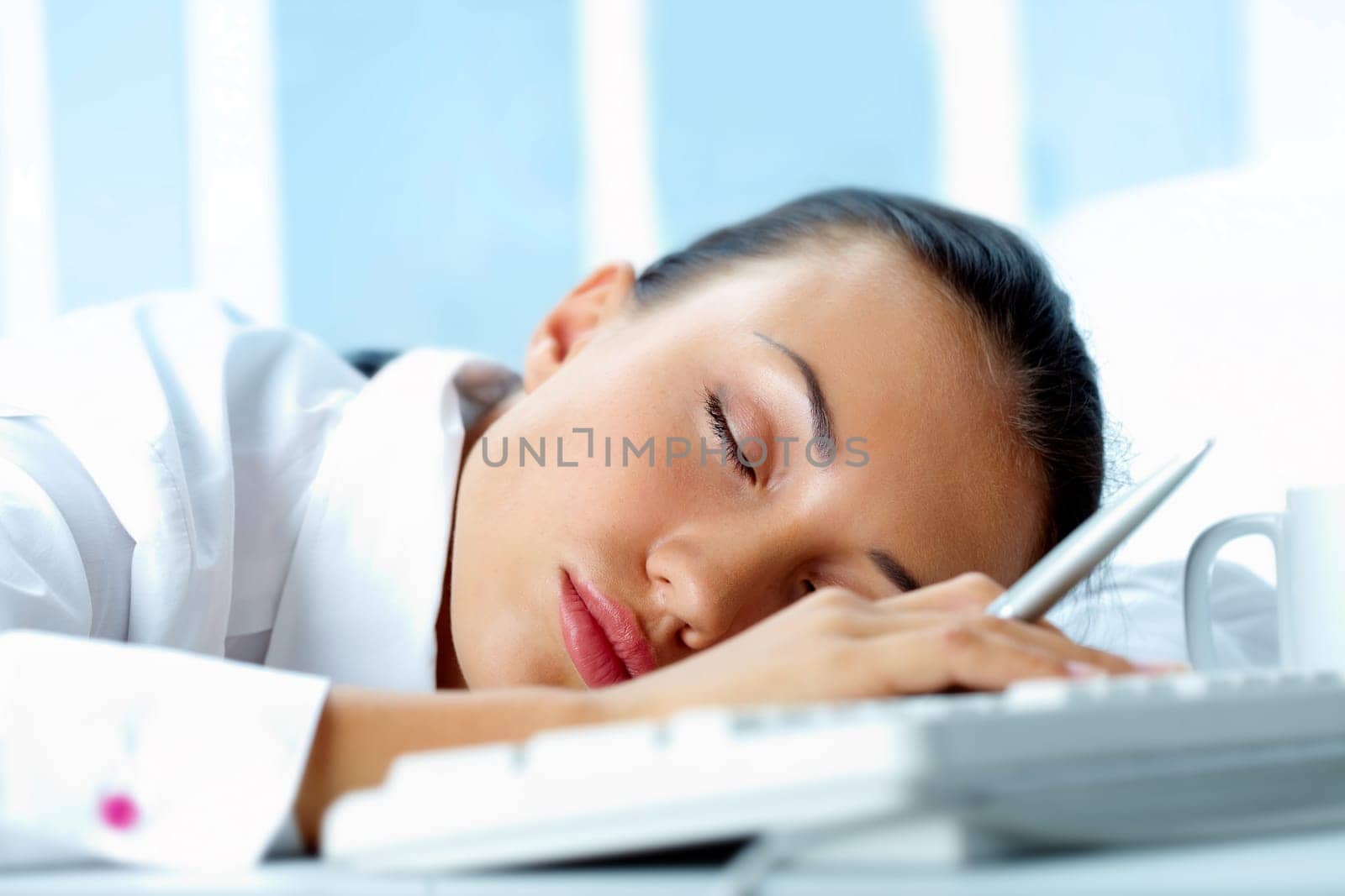 Image of young businesswoman sleeping on workplace with her head on keyboard