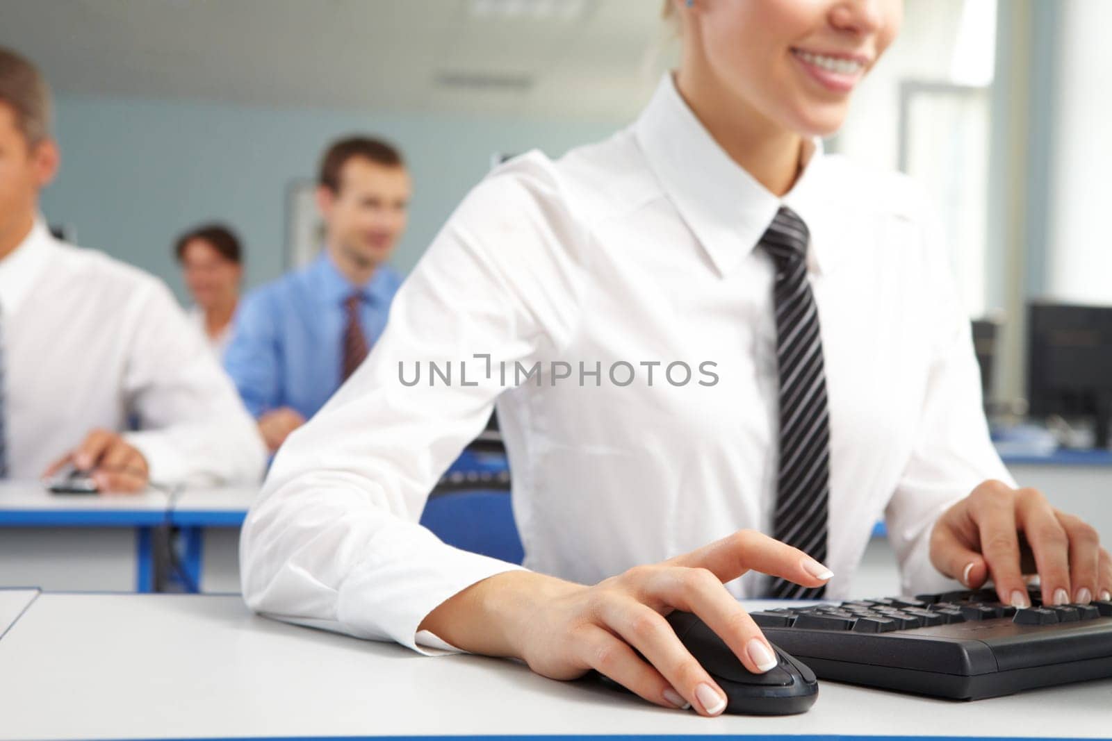 Image of female hand on mouse while typing on keyboard in a working environment