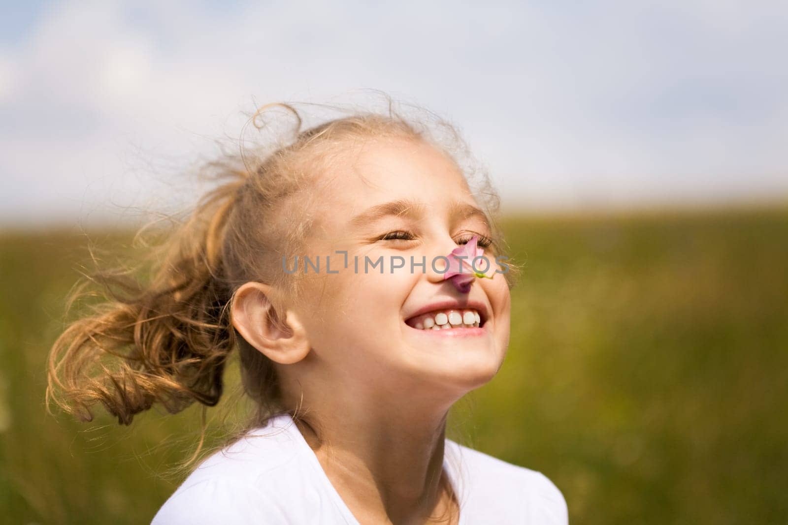 Fair-haired girl enjoying nice smell of pink flower outdoors