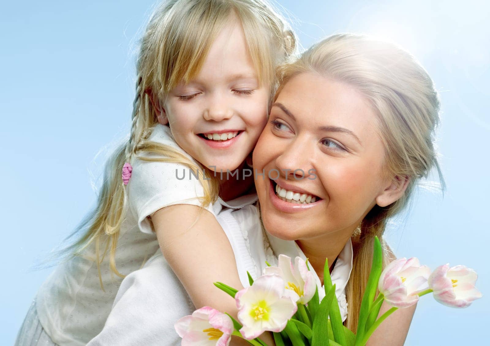 Portrait of little girl loving mother holding her and tulips