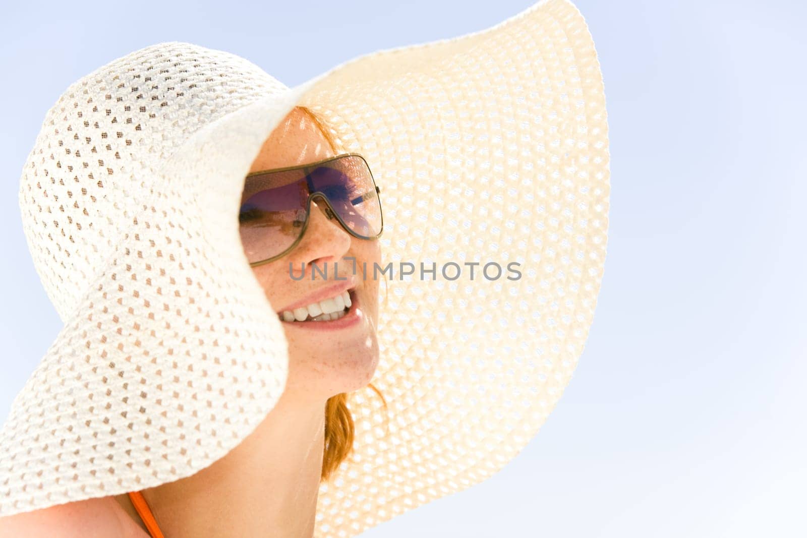 Close-up of young smiling woman wearing hat and sunglasses at rest