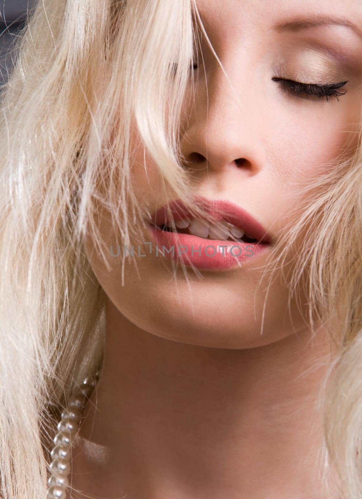 Face of blonde beautiful woman with closed eyes over black background