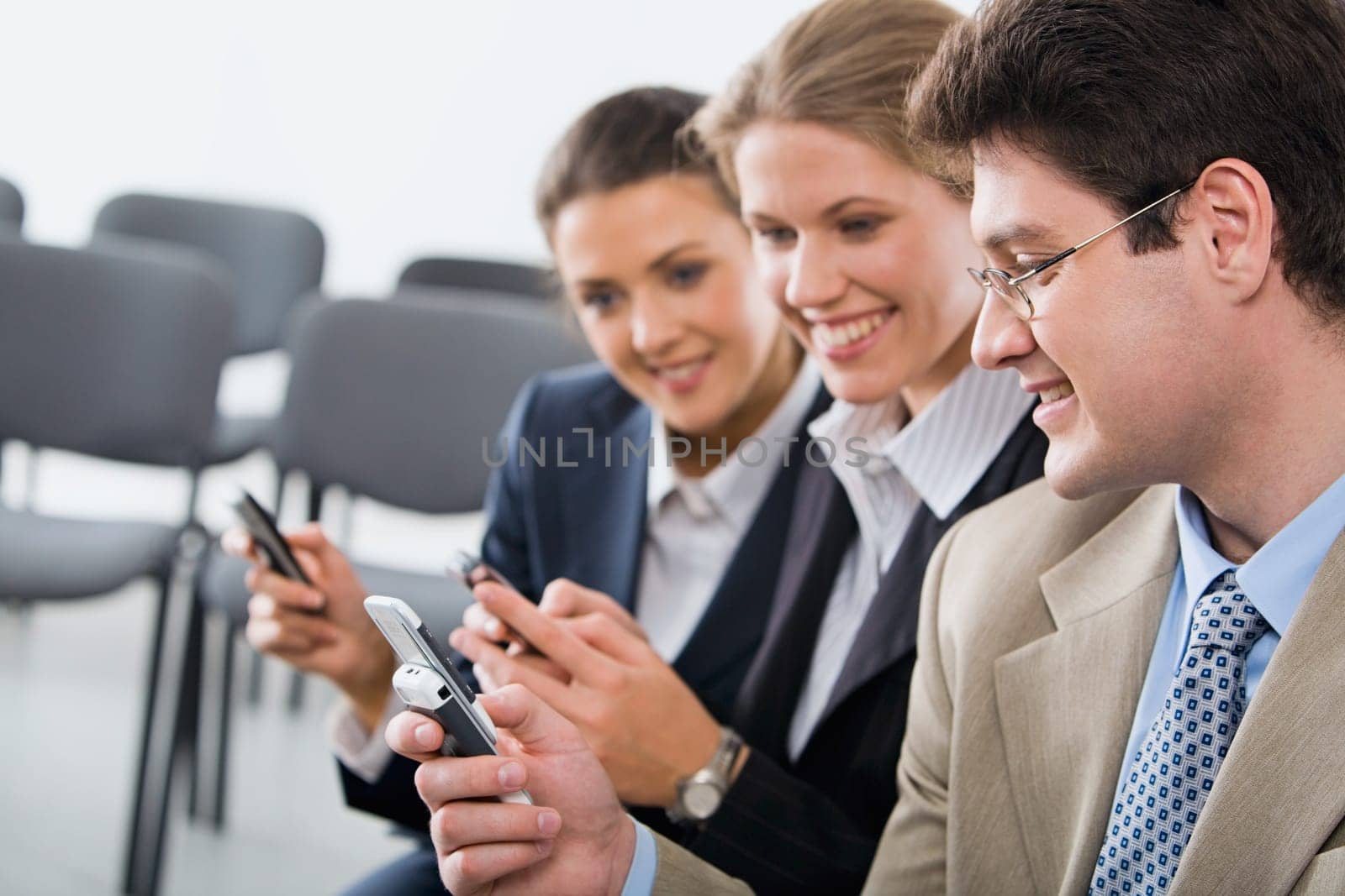 Portrait of young businesspeople exchanging an information on the mobile phones