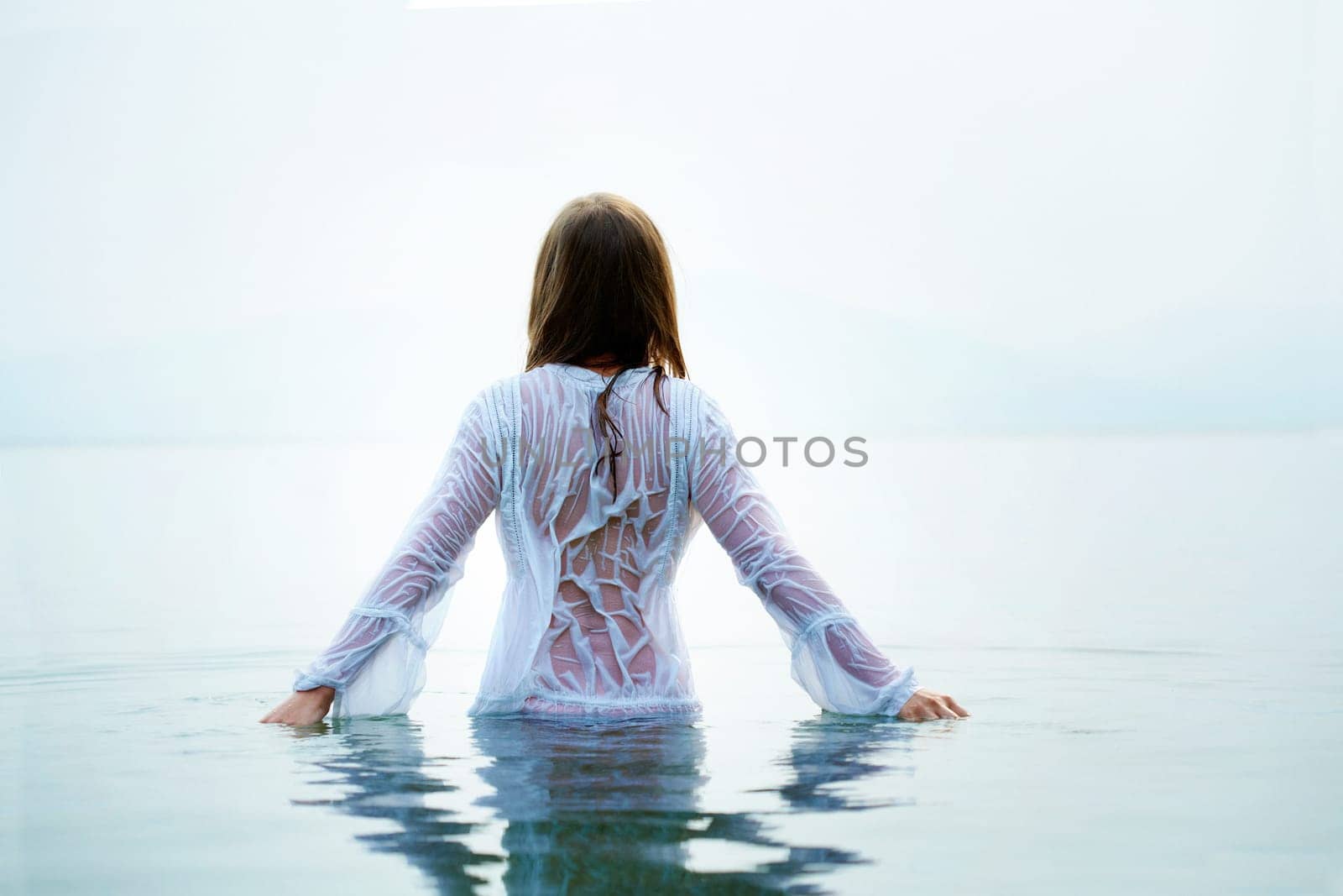Rear view of beautiful female bathing in blue water