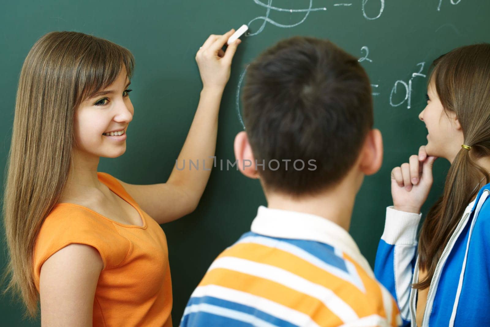 Confident student explaining formula on blackboard during algebra lesson