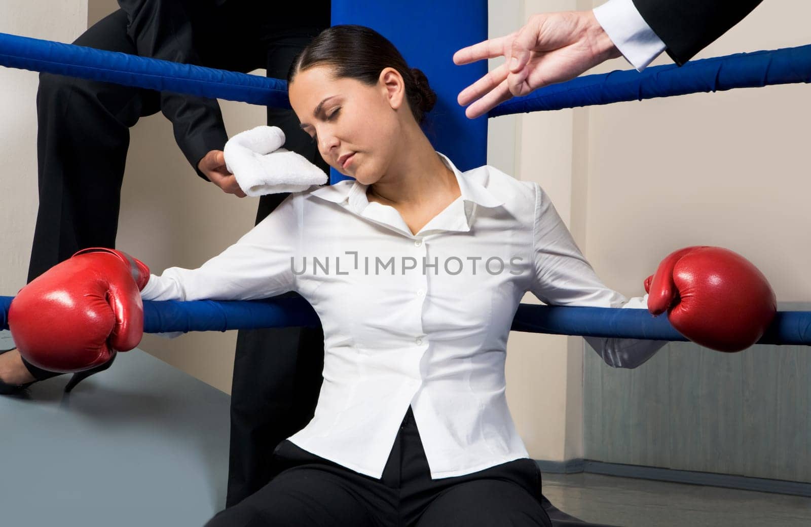 Portrait of tired businesswoman in boxing gloves sleeping on boxing ring after hard game