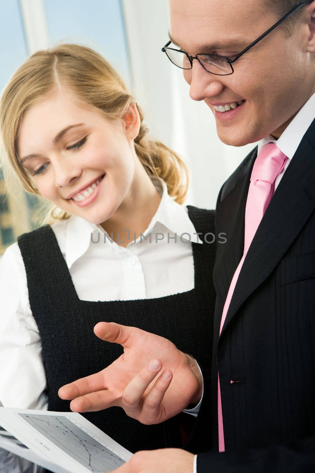 Vertical image of confident man pointing at paper while pretty businesswoman looking at it