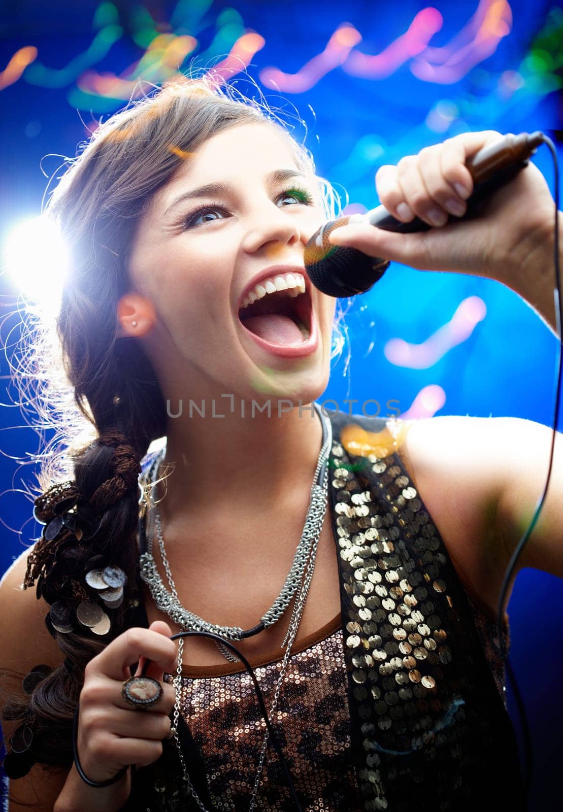 Portrait of a glamorous girl holding a mike and singing