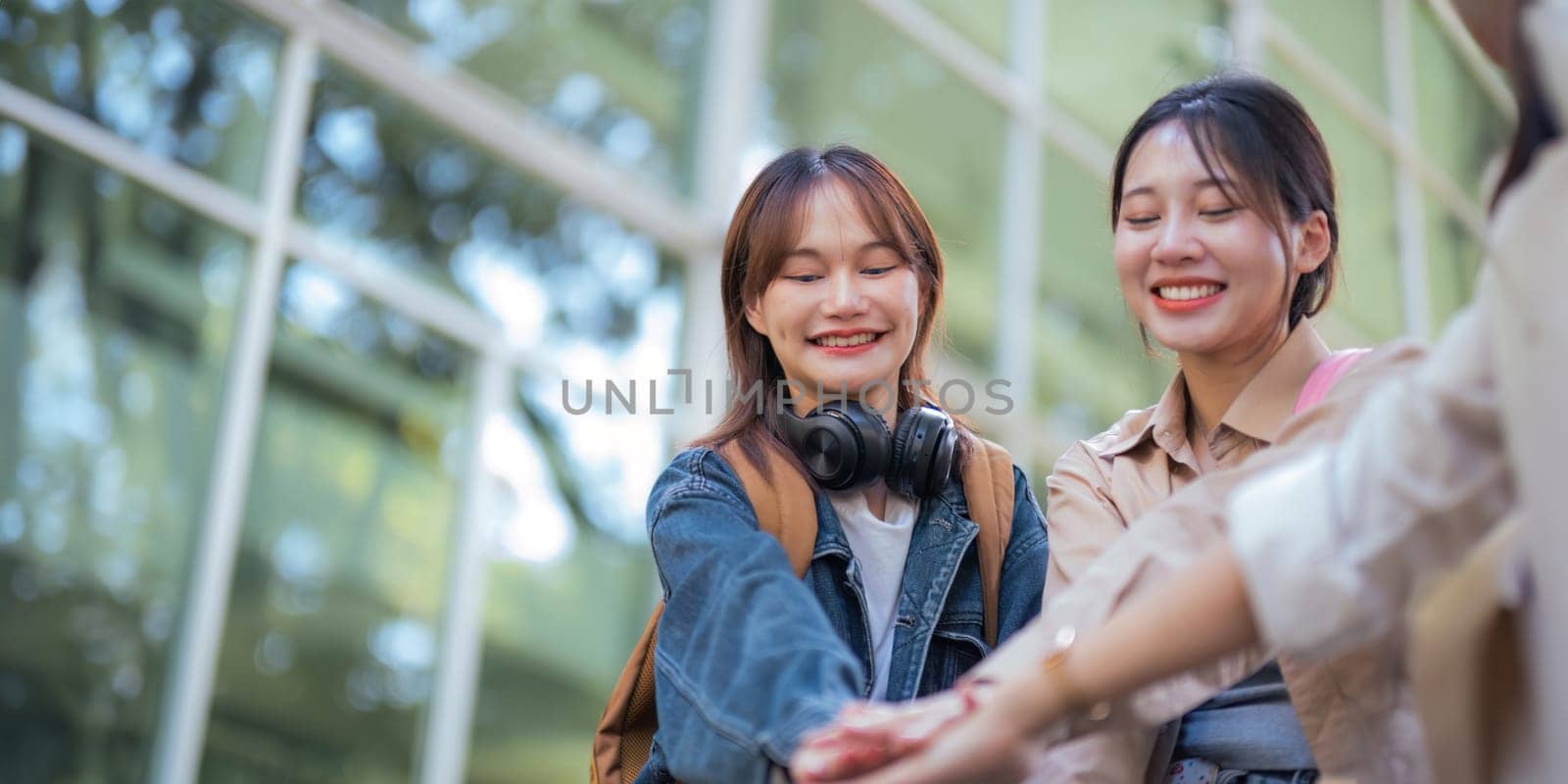 Happy females university student chat holding hands sincerely with each other after class. guy and girls wear casual clothes to university study. university College and University life concept by nateemee