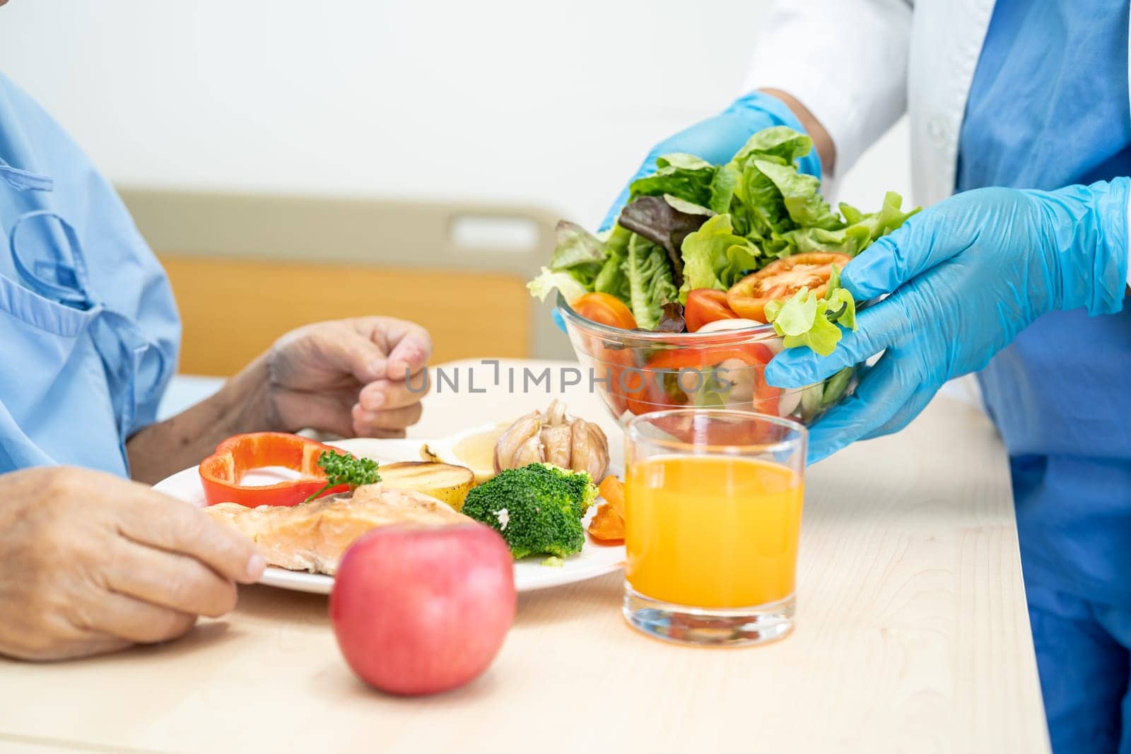 Asian senior woman patient eating Salmon steak breakfast with vegetable healthy food while sitting and hungry on bed in hospital. by pamai