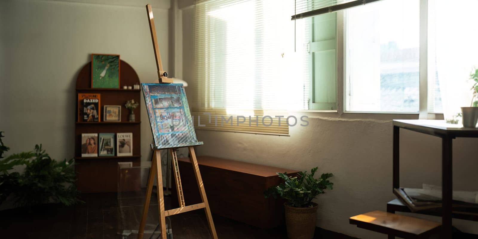 Unique artist workspace interior with bookcase, artworks, painting accessories, decoration and elegant personal stuff. Modern work room for artist..