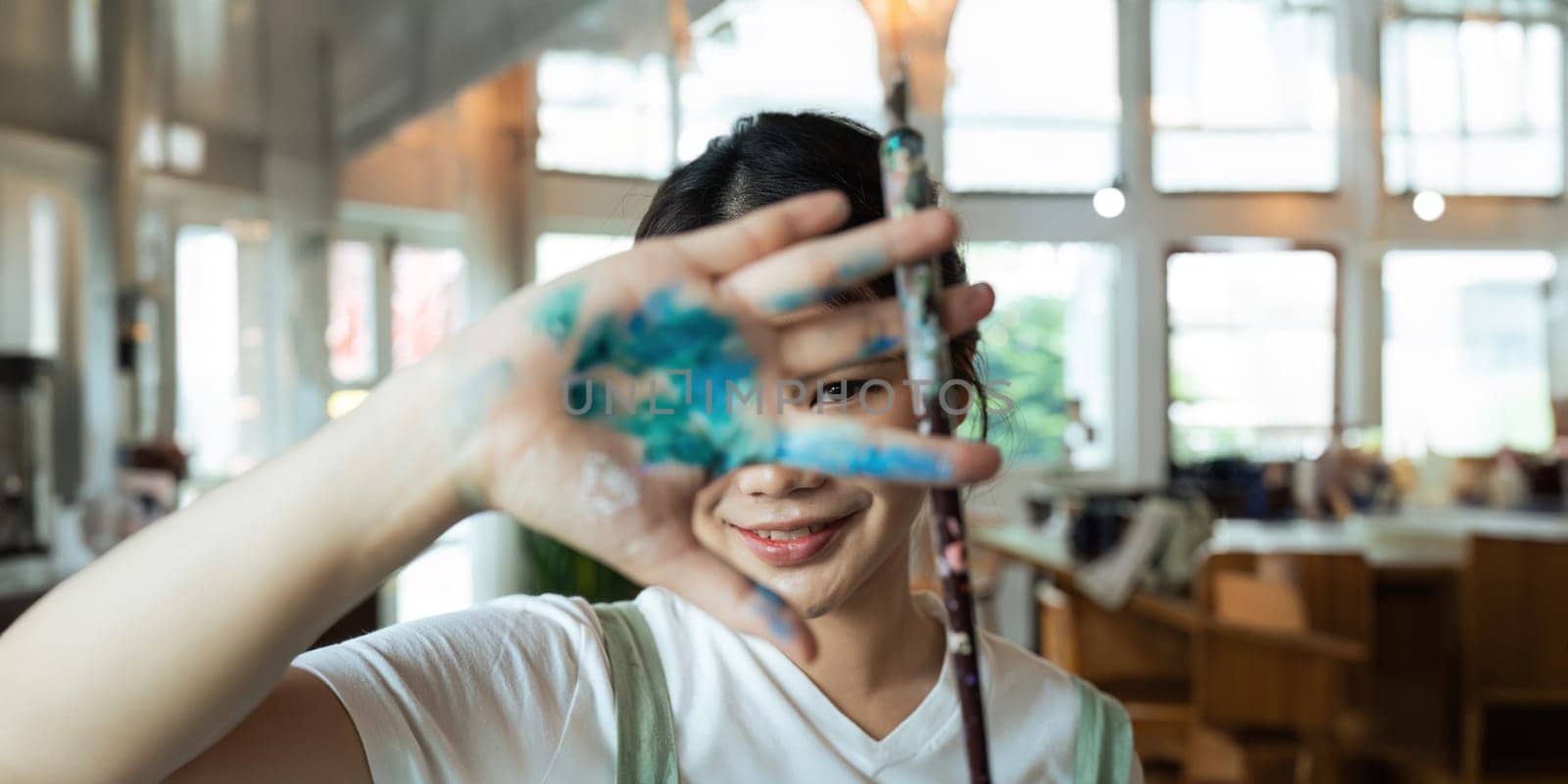 The artist creates a frame with his hands soiled with poster color paints. Portrait of a young creative artist, the process of creating a picture..