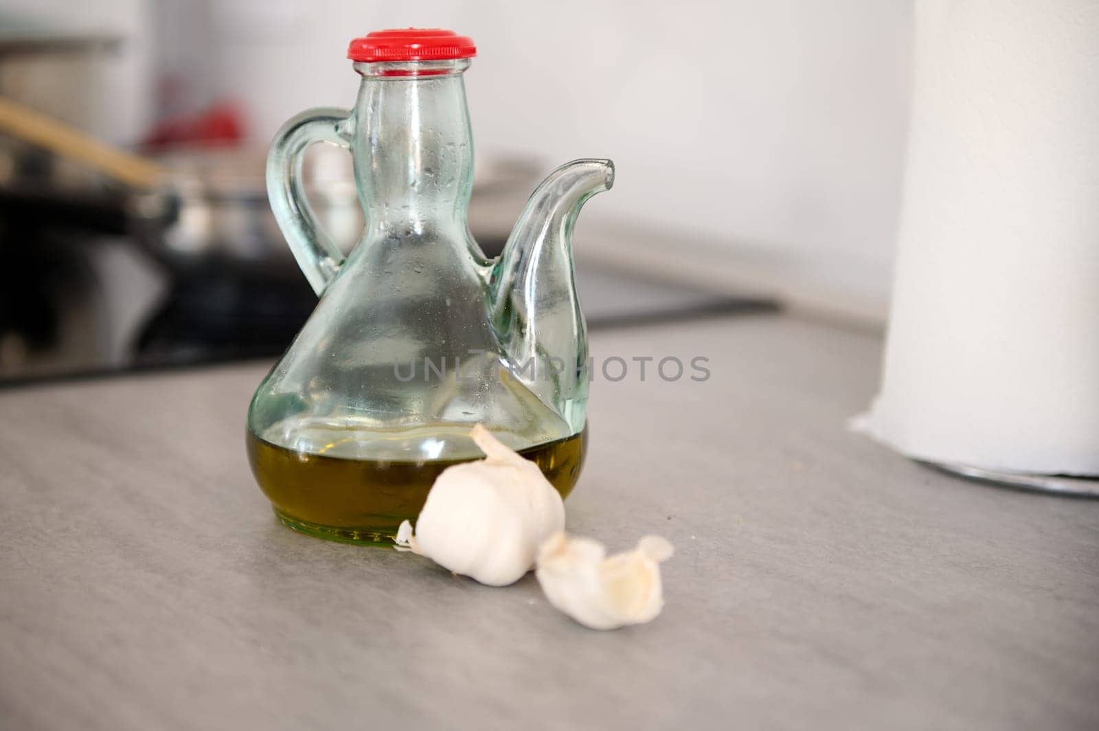 Food still life with a glass vintage bottle of fresh extra virgin olive oil and garlic cloves on the table in the home kitchen. Food and drink. Healthy organic food. Copy space for ads