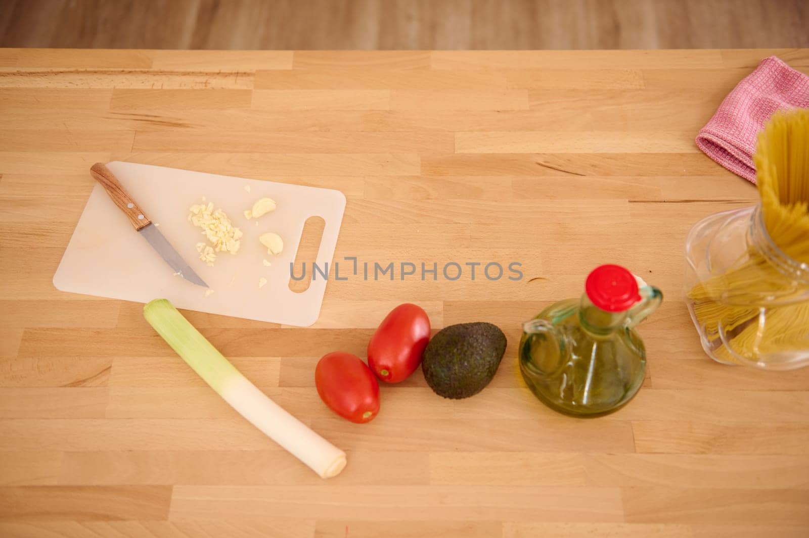 Top view of fresh vegetables, tomatoes, leek, avocado fruit and chopped garlic on the cutting board on the kitchen table. Healthy food. Dieting concept. Alimentation and nourishment. Copy ad space