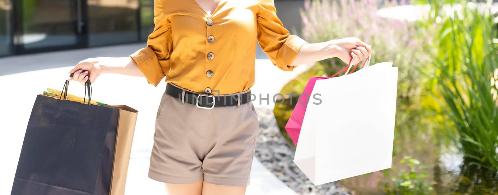 happiness, consumerism, sale and people concept - smiling young woman with shopping bags over mall background.