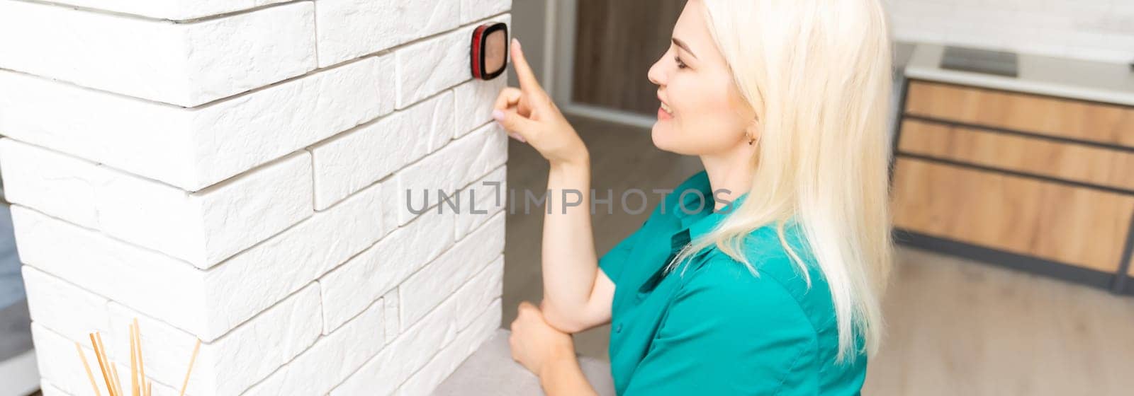 Close Up Of Woman Adjusting Wall Mounted Digital Central Heating Thermostat Control At Home.